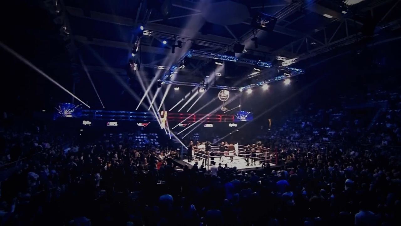 Volle arena met lichtshow tijdens een WFL-fight night — still uit de film New Era 2021–2026
